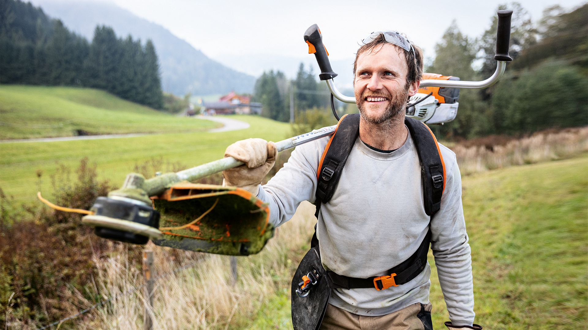 Un hombre con una desbrozadora STIHL y arnés universal Advance PLUS en un prado