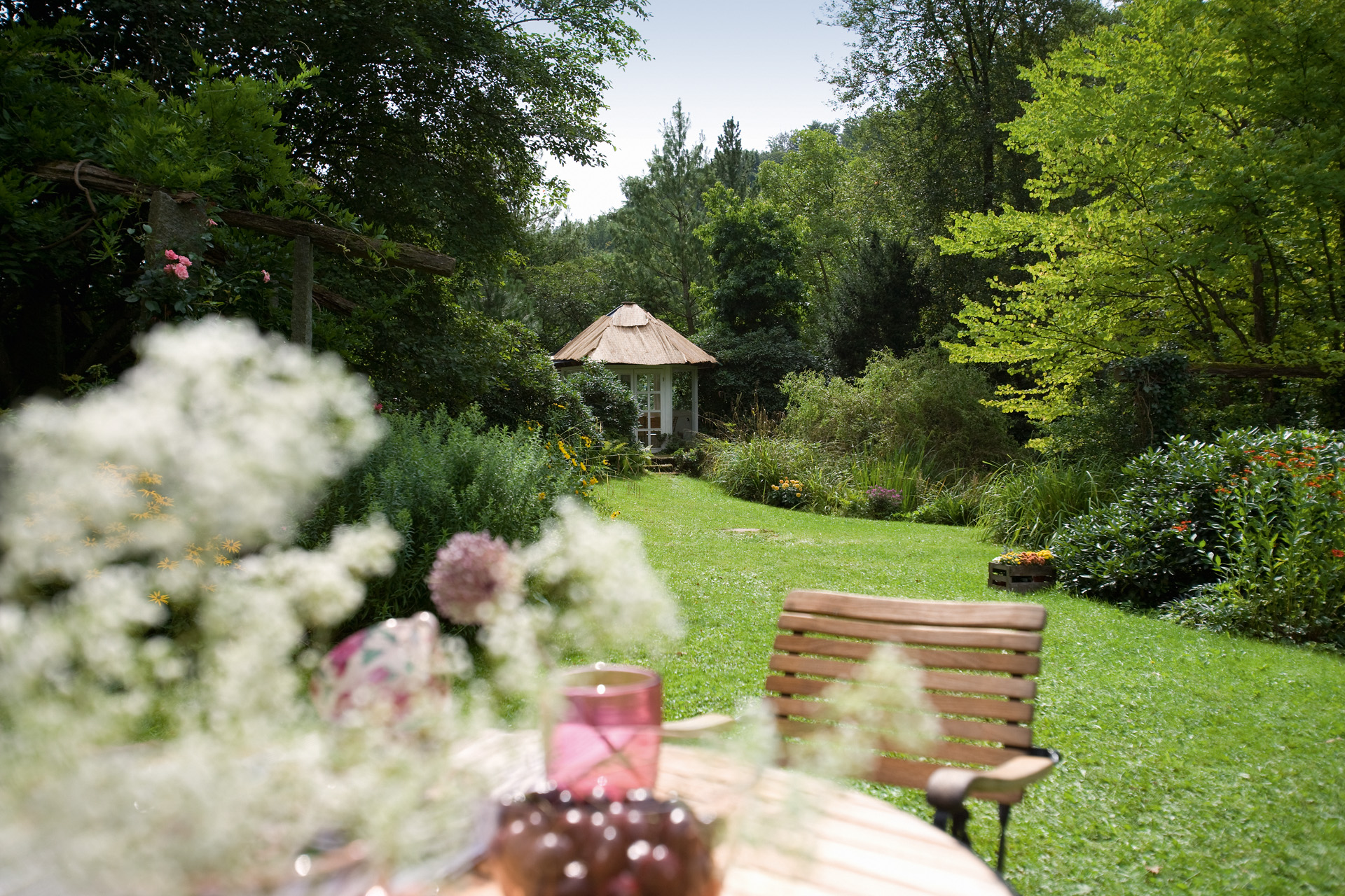 Un jardín diseñado con perfectas técnicas de jardinería. De fondo, un gran césped verde y una caseta de jardín 